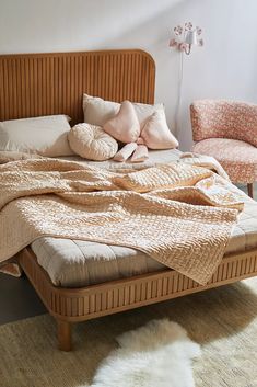 a bed with pillows and blankets on it in a room next to two chairs,