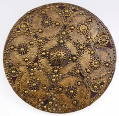 an intricately decorated plate on a white surface with gold dots and stars in the center