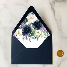 an envelope with flowers on it next to a penny