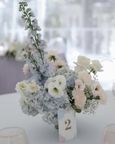 there is a vase with flowers on the table next to wine glasses and place cards