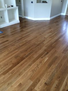 an empty room with hard wood flooring and white shelving units in the background