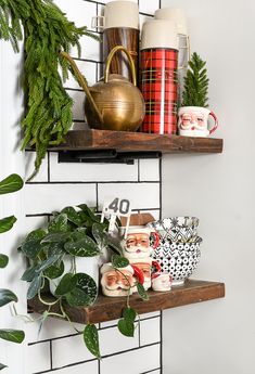 two wooden shelves with plants and mugs on them in front of a white tiled wall