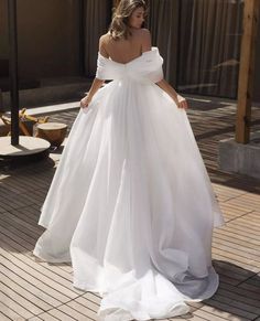 a woman in a white dress is walking down the street