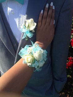 a bride and groom are holding each other's hands in front of flowers on their lapel