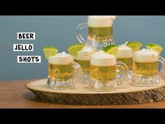 four mugs filled with beer sitting on top of a wooden tray next to lime wedges