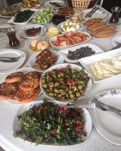 a table filled with lots of food on top of white plates and silver utensils