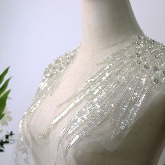 a white dress with silver sequins on it and a flower in the background