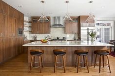 a kitchen with wooden cabinets and stools next to a center island in the middle