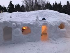 an igloose with two people in it and lights on the inside, surrounded by snow