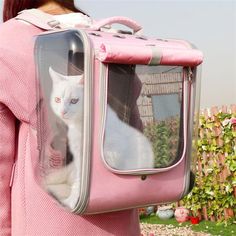 a woman holding a pink suitcase with a white cat in it's back pocket