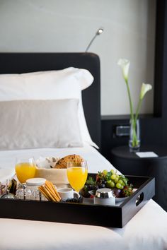 a tray filled with food on top of a bed next to a vase full of flowers