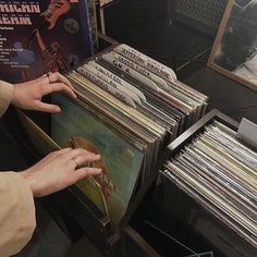 a person holding a record player in front of a stack of records