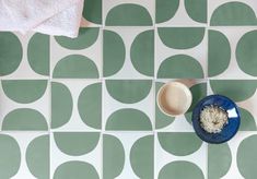 a blue bowl with rice in it next to a white and green wall tile pattern