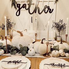 the table is set with white pumpkins and greenery