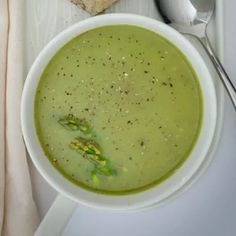 a bowl of broccoli soup next to some bread