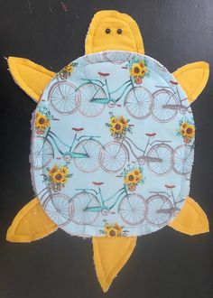 a yellow turtle with sunflowers and bicycles on it's back, sitting in front of a black background