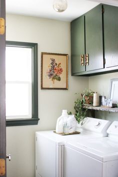 a washer and dryer sitting in a room next to a window with green cabinets