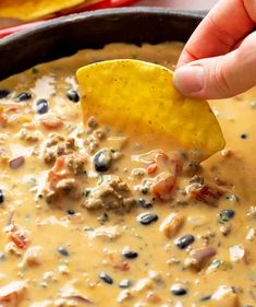 a hand dipping a tortilla chip into a bowl of quesadilla soup