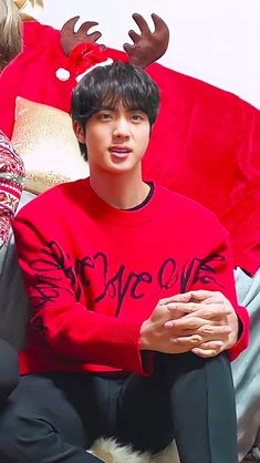 a young man wearing a red sweater with reindeer antlers on it