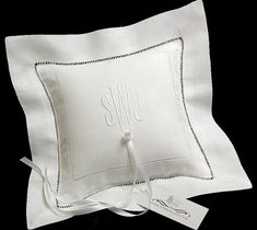 two white pillows with embroidered monogrammings on them and one is tied to the pillow