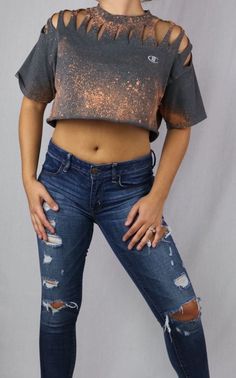 a woman in ripped jeans and a crop top posing for the camera with her hands on her hips