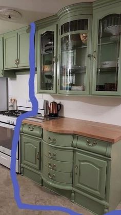 a kitchen with green painted cabinets and a white stove top oven in the middle of it