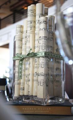 a stack of candles sitting on top of a table covered in sheet music notes and green ribbon