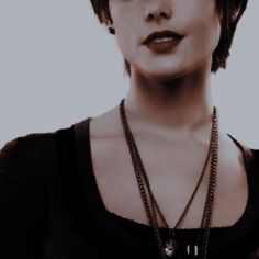 a woman with short hair wearing a black shirt and some necklaces on her neck