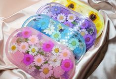 three plastic containers filled with colorful flowers on top of a white cloth covered tablecloth