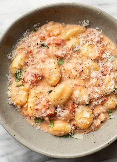 a bowl filled with pasta and sauce on top of a marble countertop next to a spoon