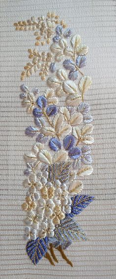 an embroidered piece of cloth with blue and white flowers