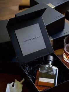 an empty glass and bottle in a black box on a table next to some other items