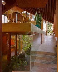 the inside of a house with stairs leading up to an upper floor area and plants on either side