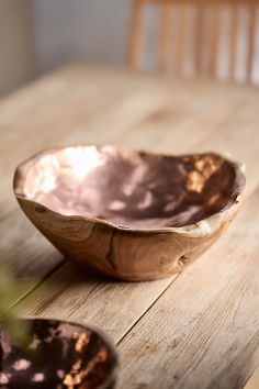 a bowl sitting on top of a wooden table next to a potted green plant