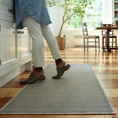 a person standing on top of a rug in a kitchen