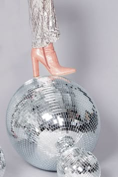 a woman standing on top of a disco ball with her legs up in the air