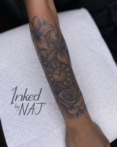 a woman's arm with a clock and flowers tattooed on the side of it