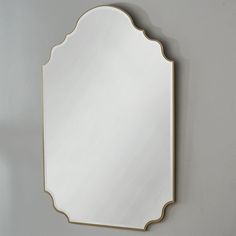 a mirror hanging on the wall in front of a gray wall with a gold frame