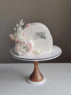 a white cake with flowers on top sitting on a plate