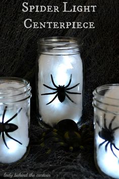 three mason jars with spider lights in them on a black table cloth and the words, spider light centerpiece