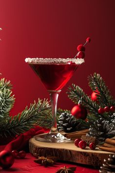 a red drink in a martini glass with a garnish on the rim and pine cones