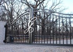 an iron gate with the letter b on it and a brick wall in front of it