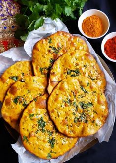 four pieces of bread with herbs on top and two bowls of spices in the background