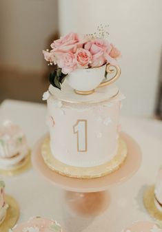 there is a cake with flowers on the top and two small cupcakes next to it