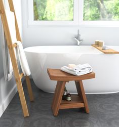 a white bath tub sitting next to a wooden stool