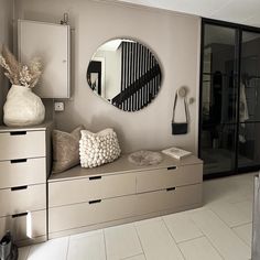 a living room filled with furniture and a round mirror on the wall over a dresser