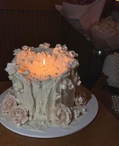 there is a white cake with flowers on the plate and a candle in the middle