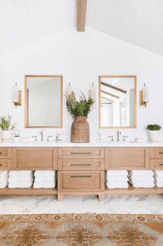 a bathroom with two sinks, mirrors and towels on the counter top next to each other