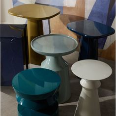 several different colored tables and stools on the floor