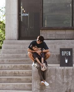 a man and woman hugging each other in front of a building with steps leading up to it